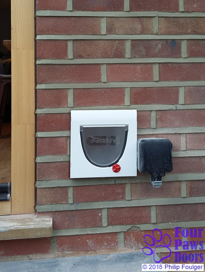 Cat flap installed in a tight space next to electric mains socket